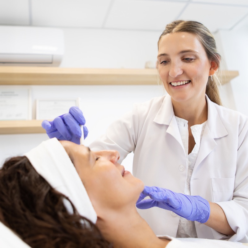 Profissional de jaleco marcando a face da paciente antes da aplicação de bioestimulador